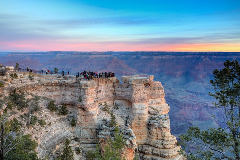 sunset image of the grand canyon where passengers are standing on the edge
