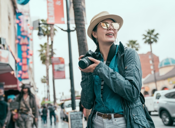 happy woman traveler in sunglasses walking on hollywood boulevard take photo for memory trip usa