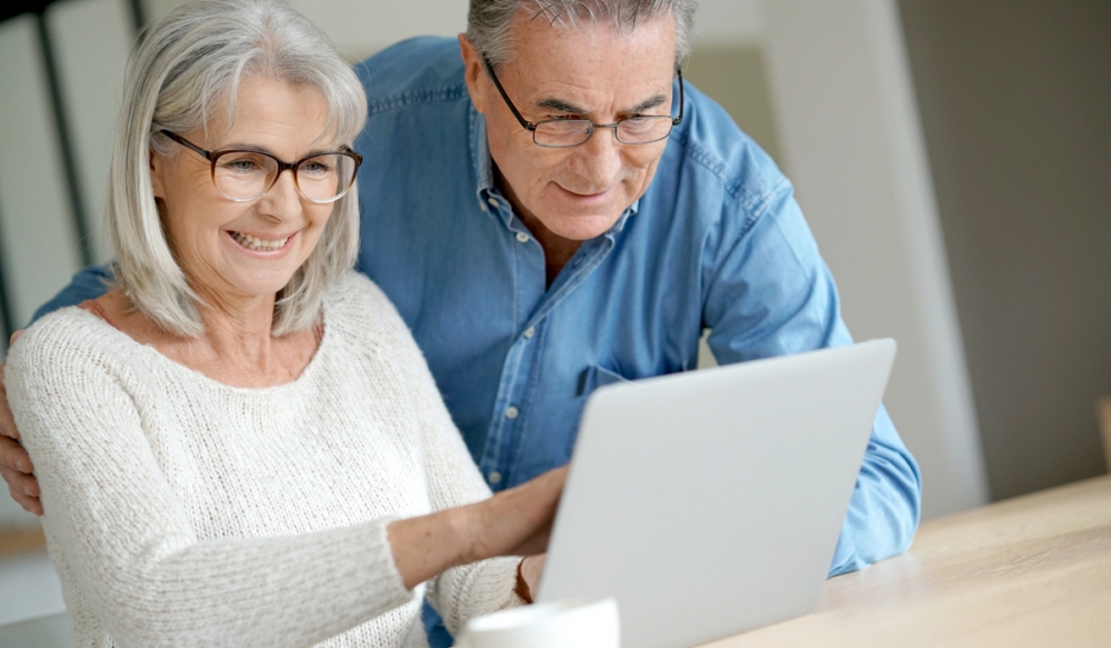 a happy couple on a computer planning their train trip